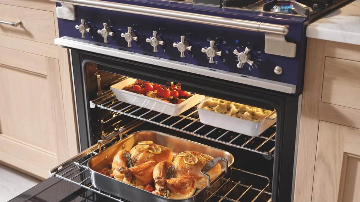A cobalt blue AGA cast-iron range with the ovens open on a roast