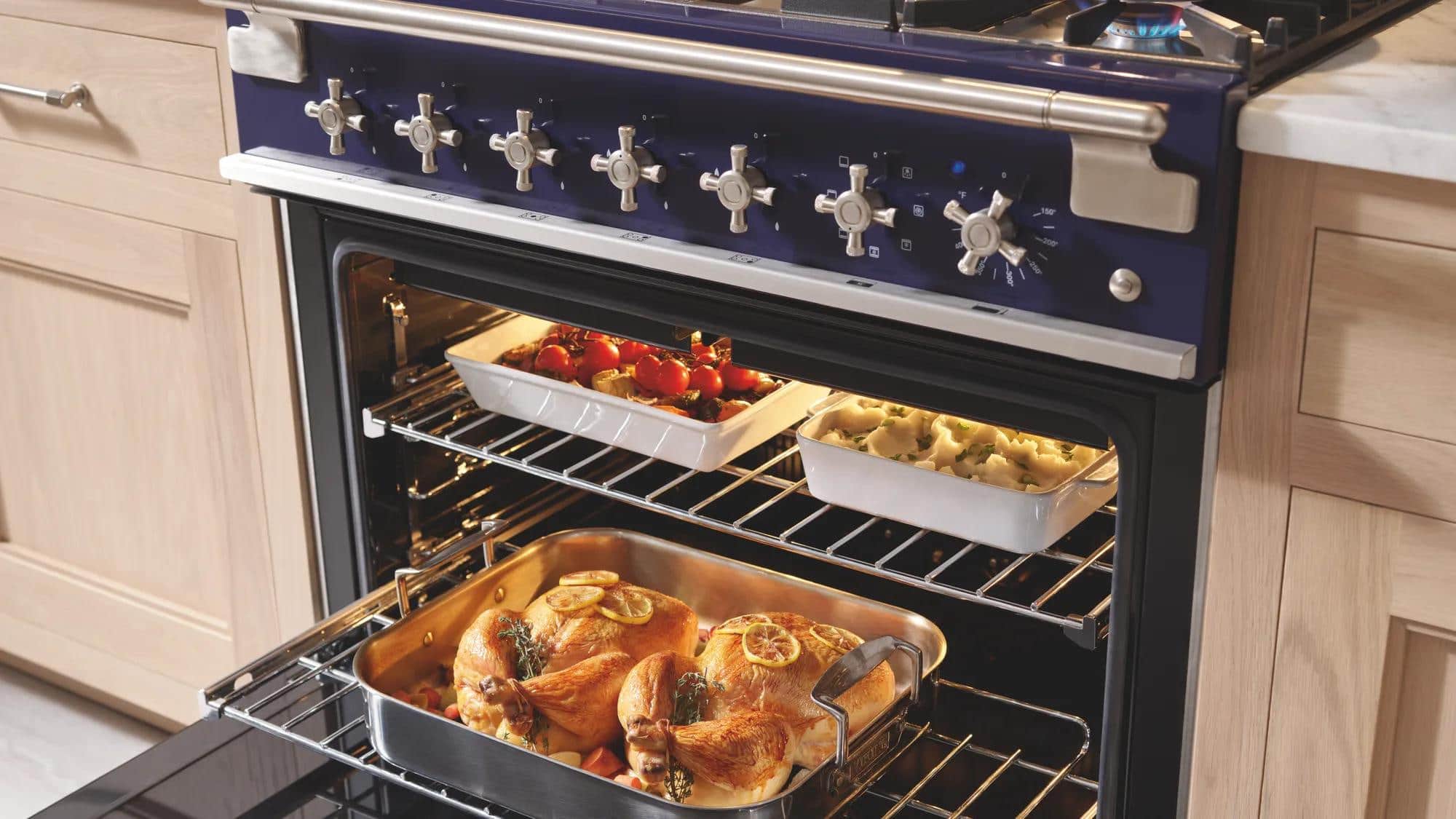 A cobalt blue AGA cast-iron range with the ovens open on a roast
