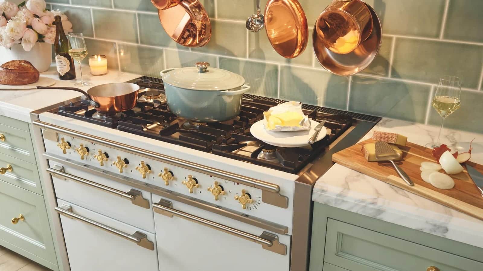 A cream AGA cooker with copper pans against green tile