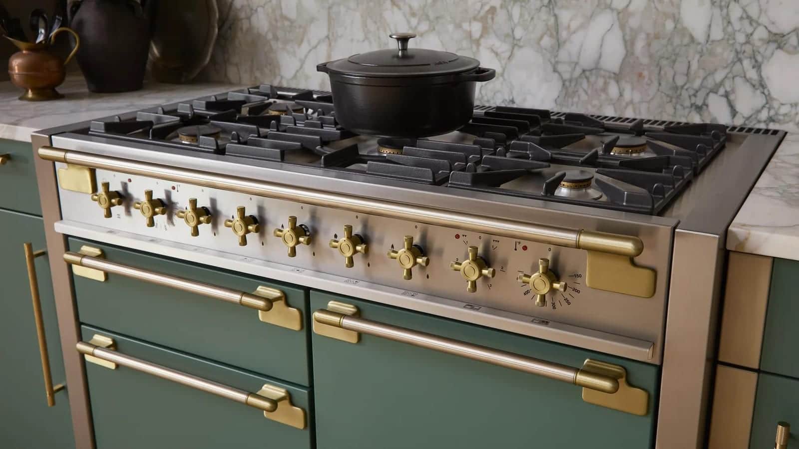 An AGA rangetop with brass controls in a mineral green kitchen