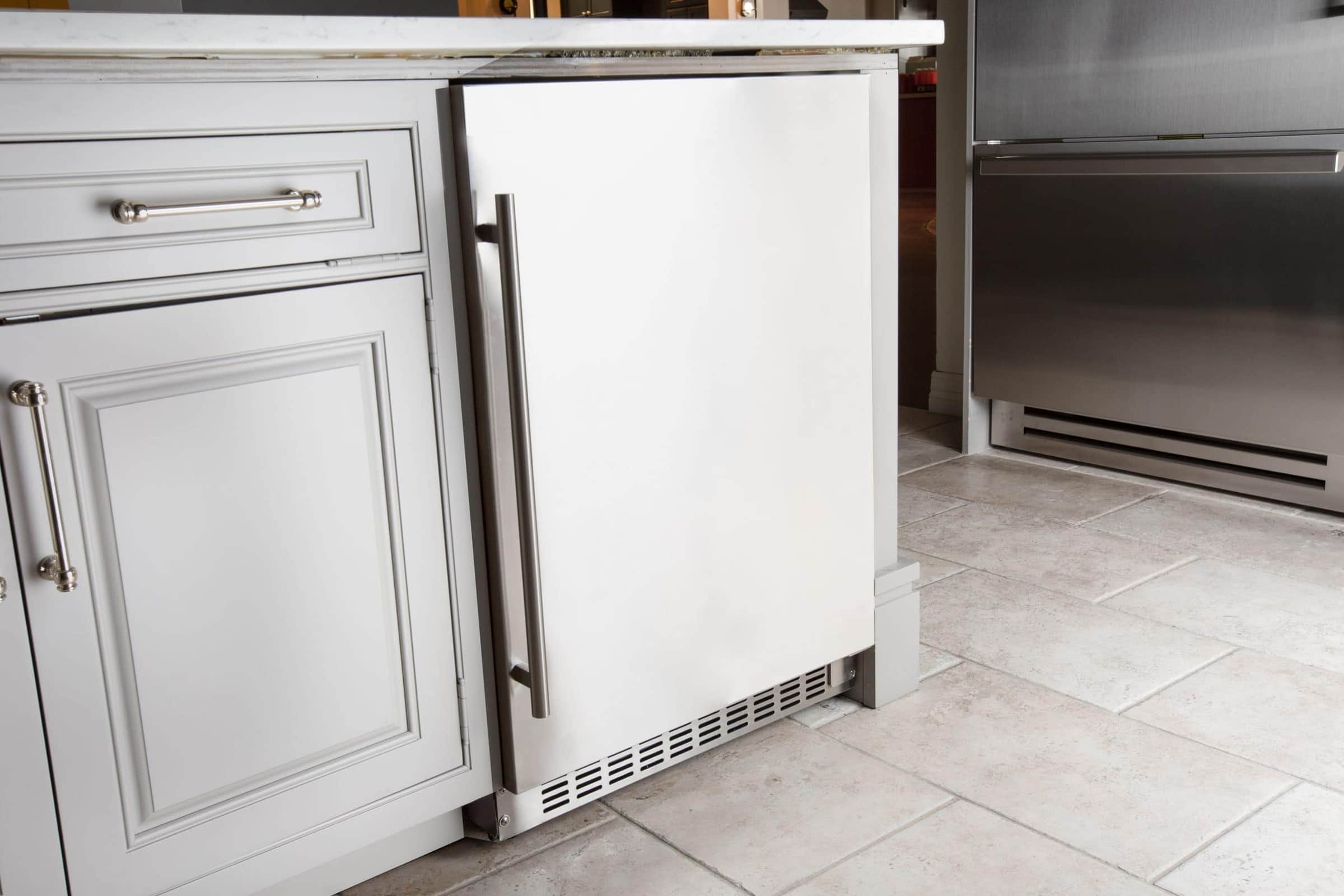A stainless Azure undercounter refrigerator set into white shaker cabinetry