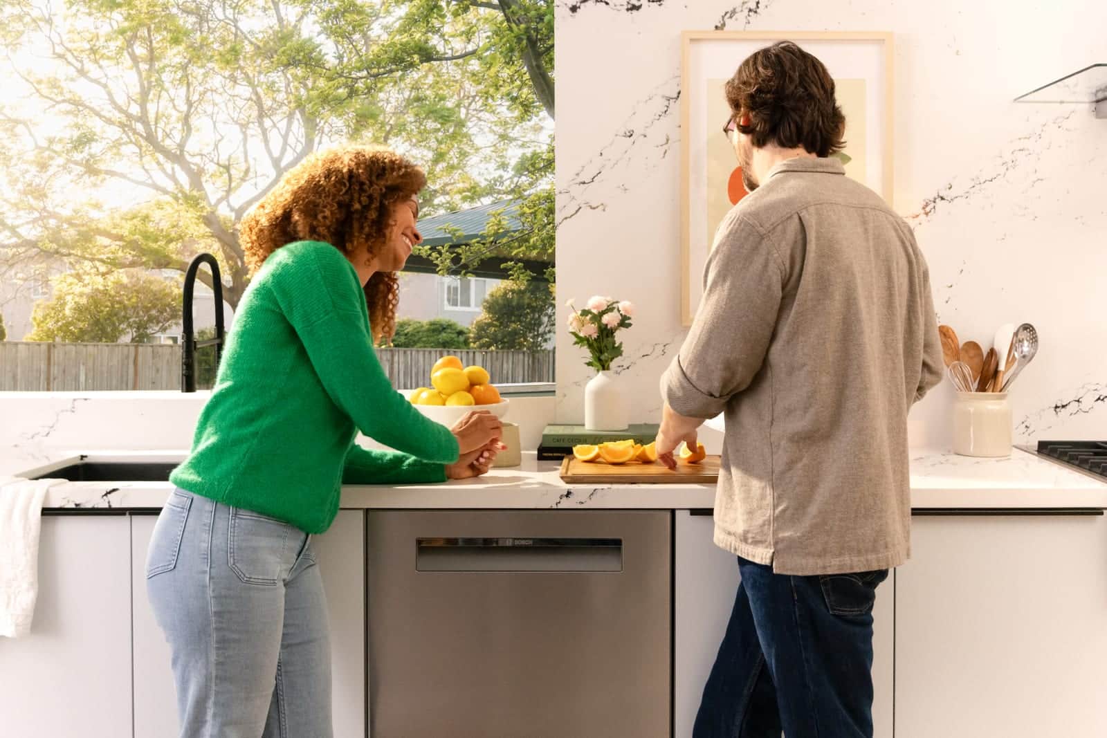 A couple preparing citrus in a white Bosch kitchen