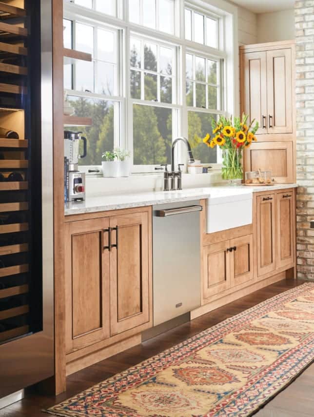 A panel-ready Cove dishwasher built into an oak kitchen beside a farmhouse sink
