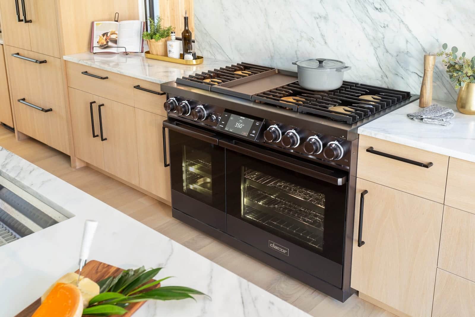 A black Dacor range in an oak kitchen with a marble island