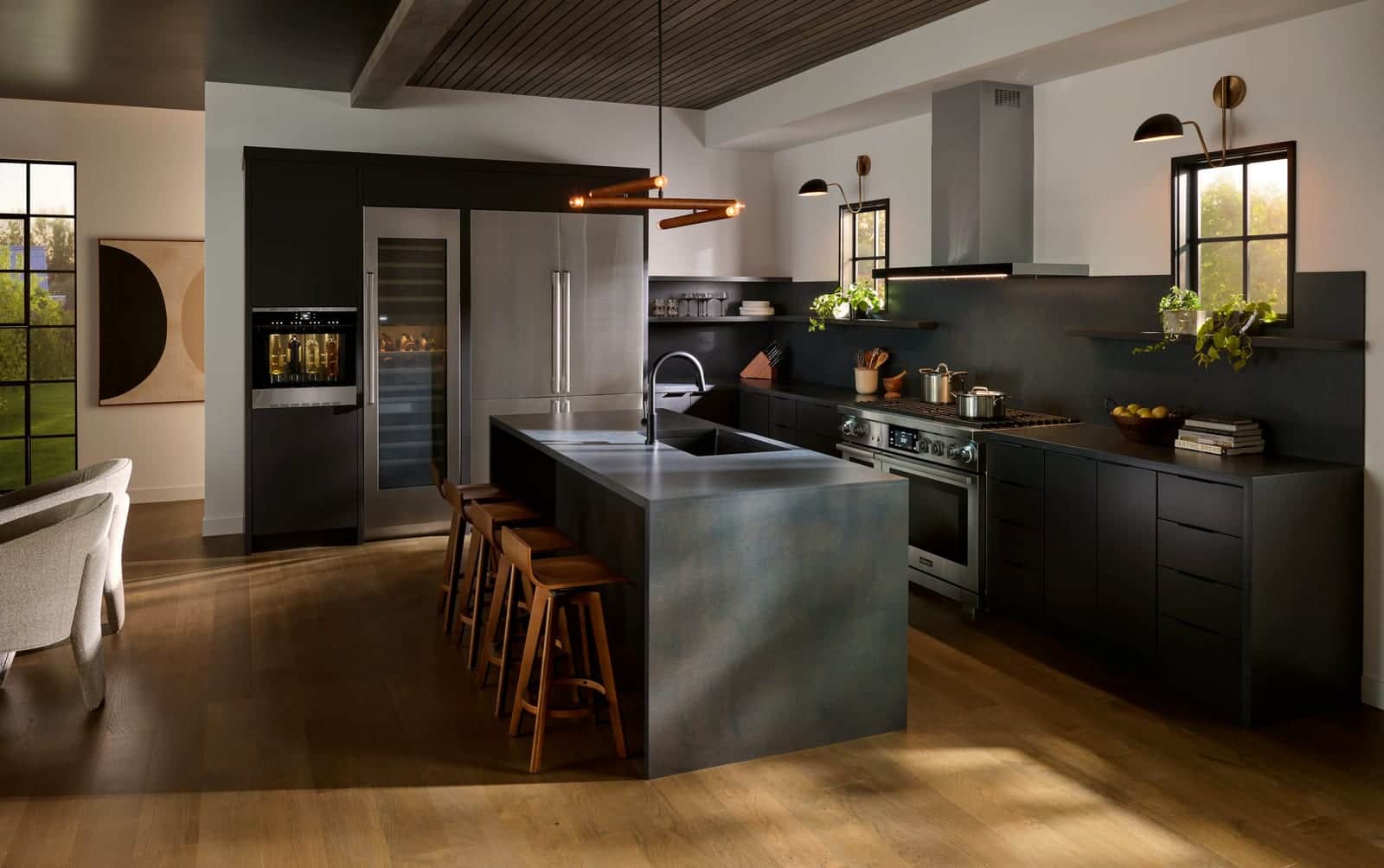 A graphite Dacor kitchen with a concrete-look island and wood stools