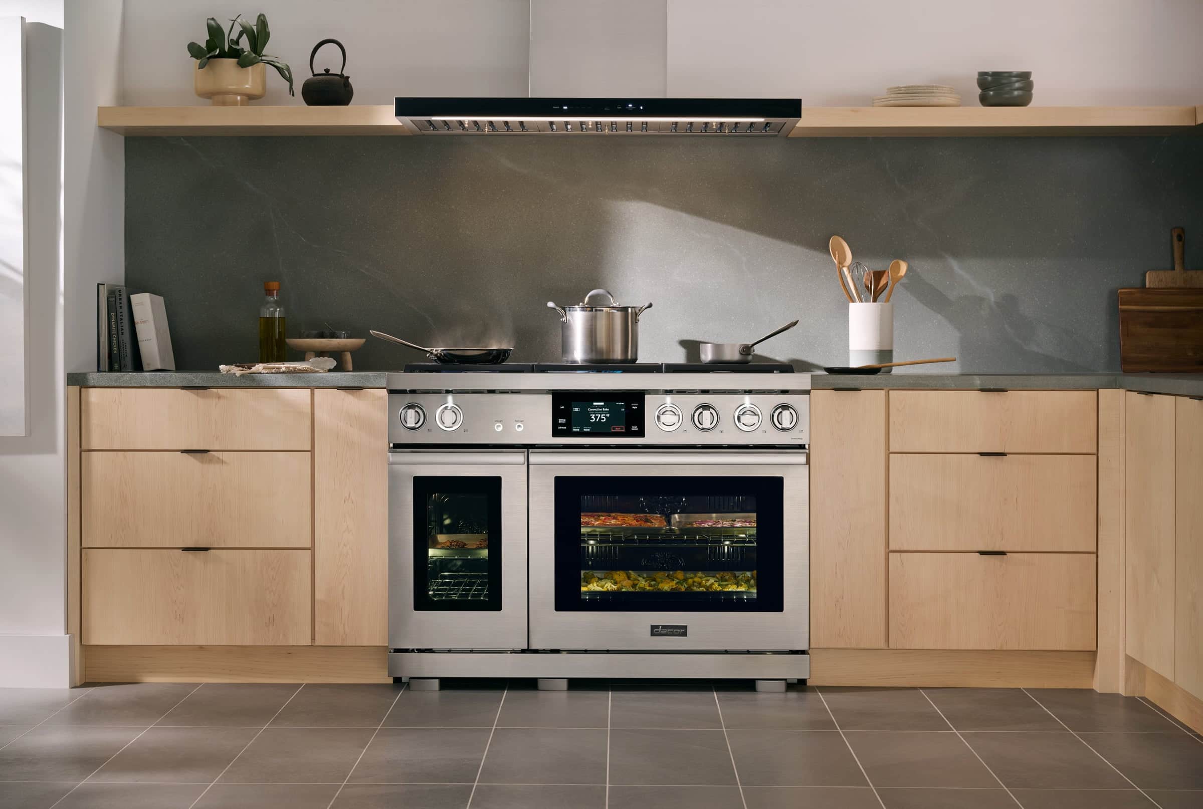 A Dacor dual-oven range roasting vegetables in a pale wood kitchen
