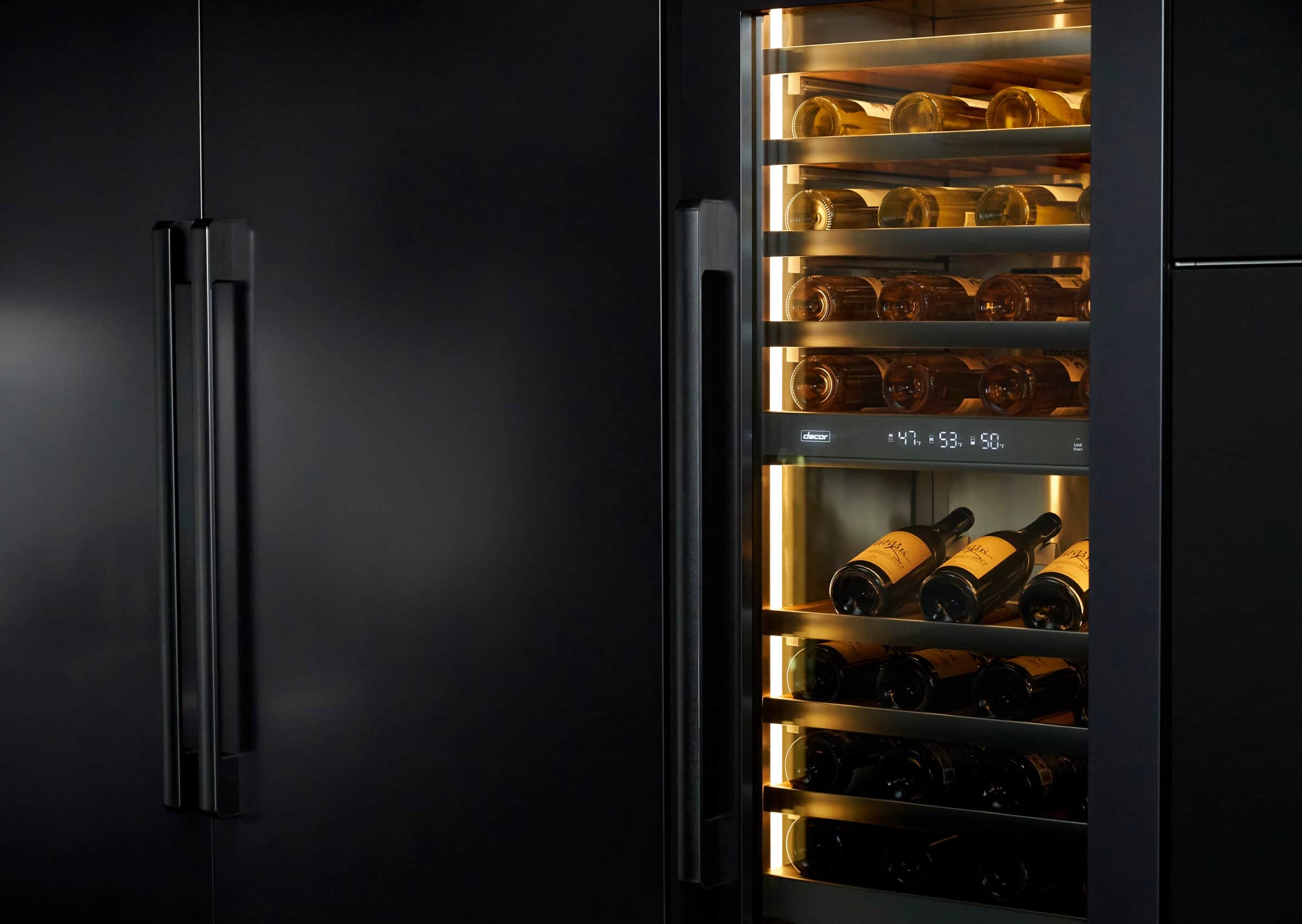 An illuminated Dacor wine column beside black cabinetry