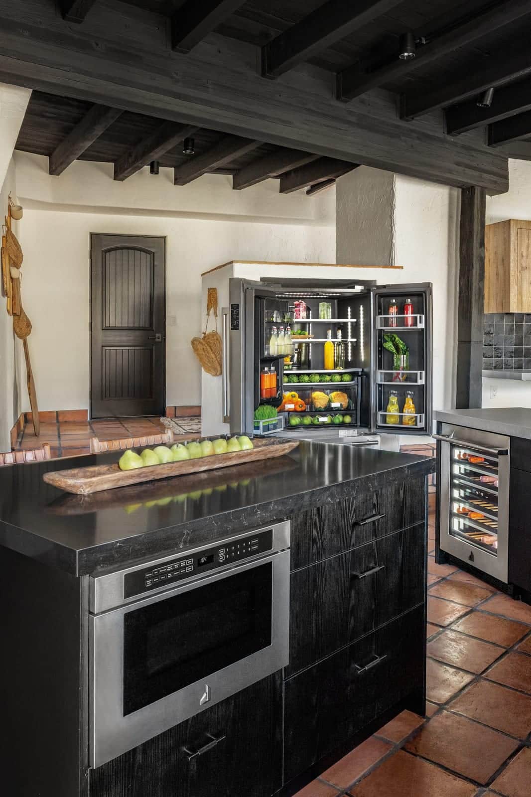 A black JennAir island with a built-in microwave drawer against a terracotta wall