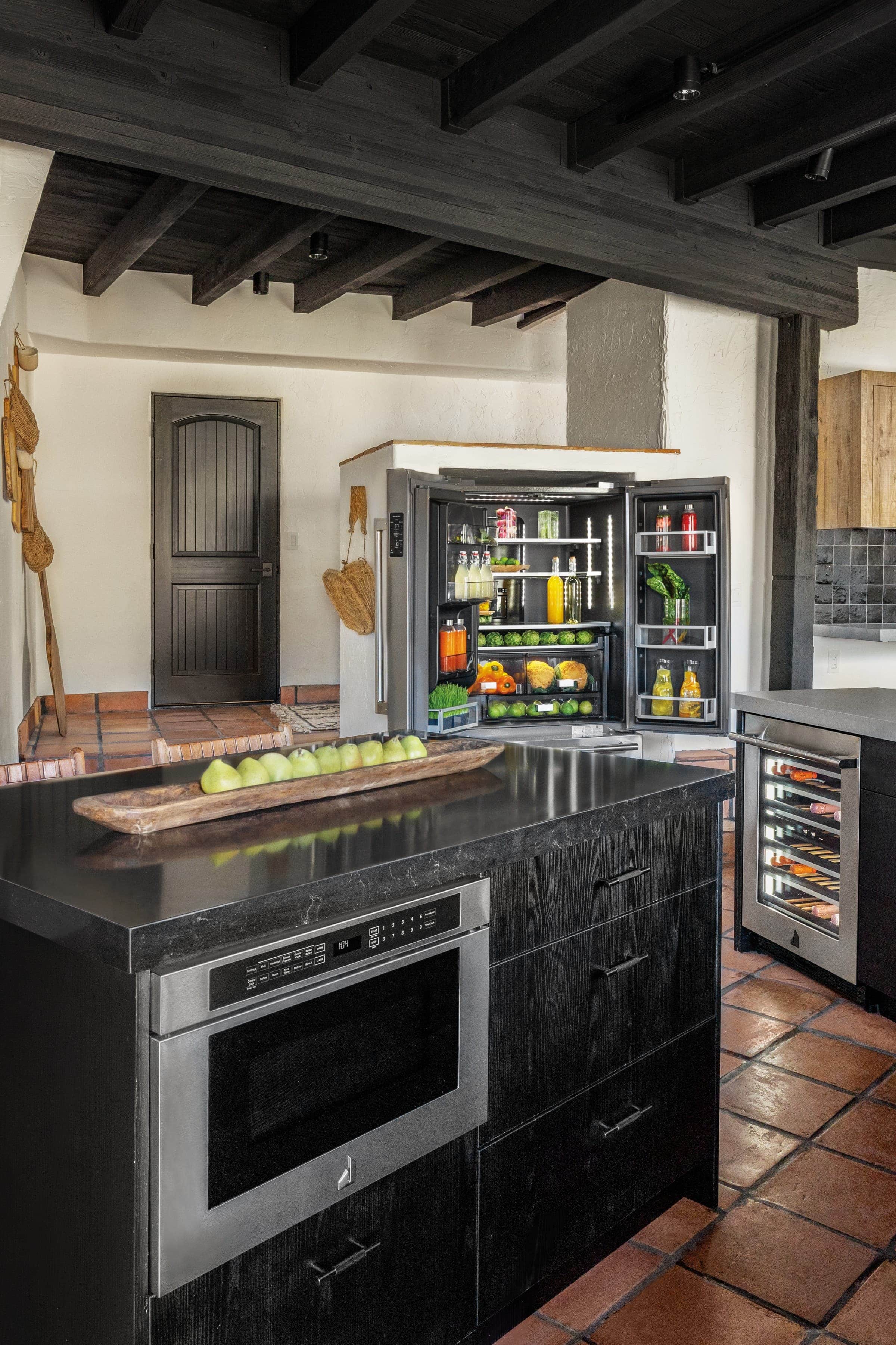 A black JennAir island with a built-in microwave drawer against a terracotta wall
