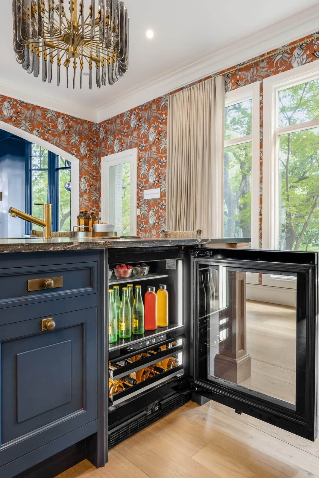 A JennAir beverage centre with an open glass door built into a blue kitchen island