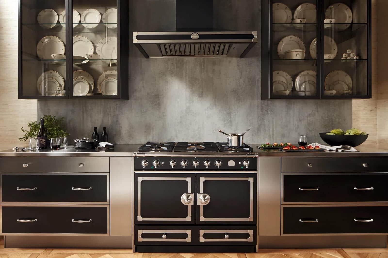 A black La Cornue range against a copper backsplash in a dark cabinet kitchen