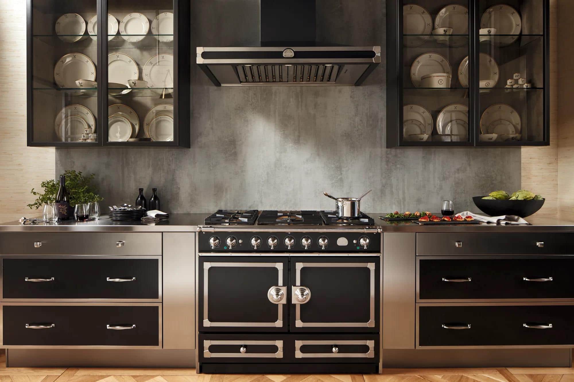 A black La Cornue range against a copper backsplash in a dark cabinet kitchen