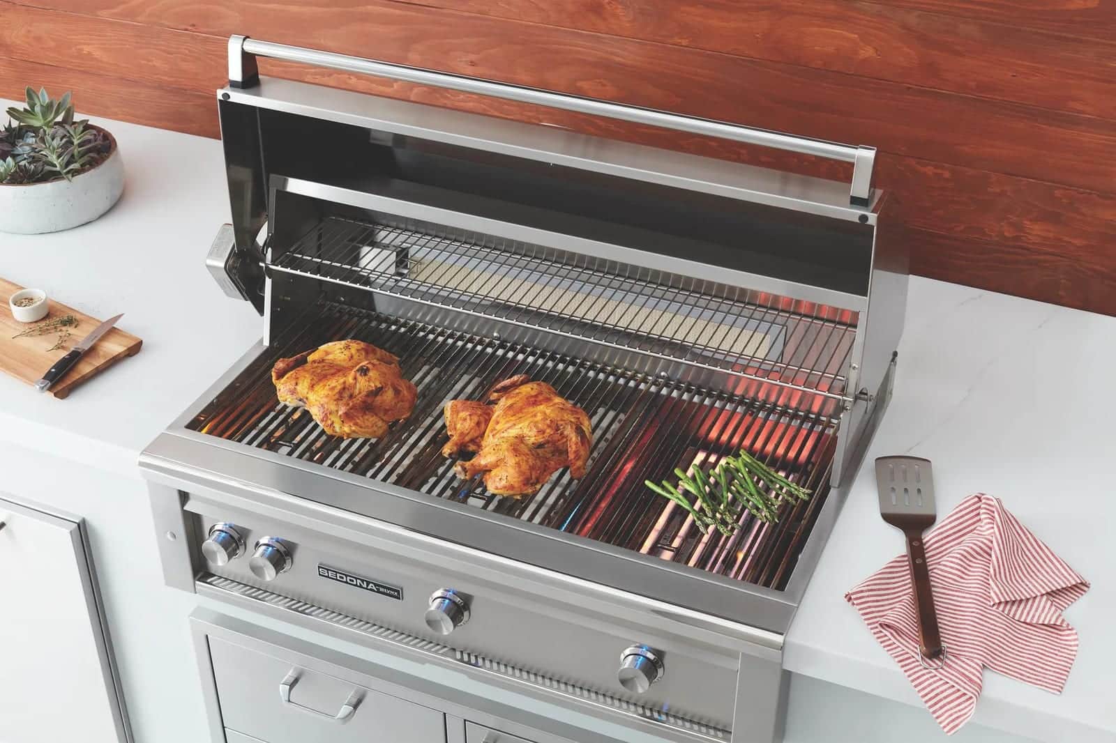 A built-in Lynx grill searing spatchcocked chickens in an outdoor kitchen
