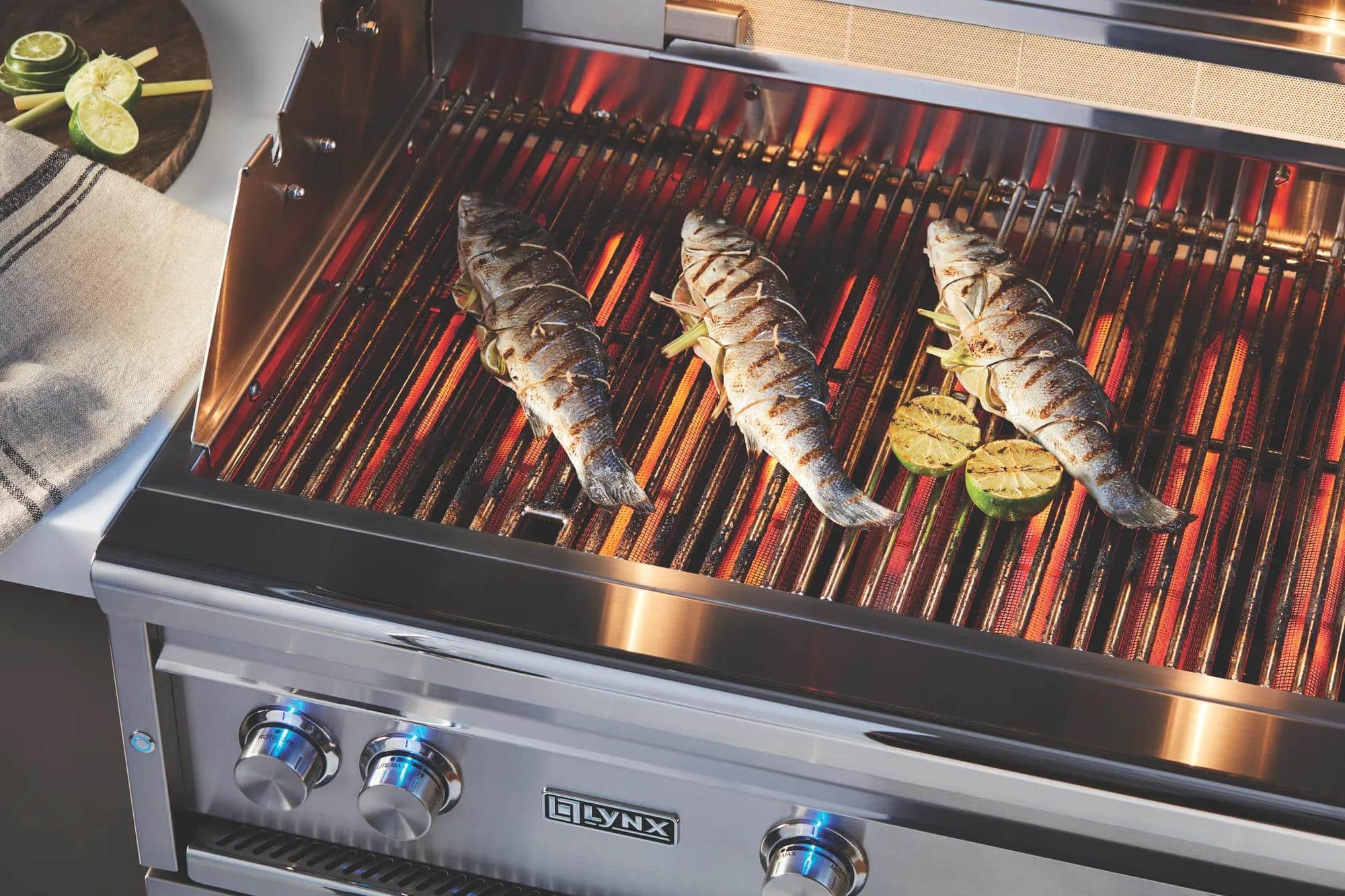 Three whole fish on the grates of a Lynx grill over glowing burners