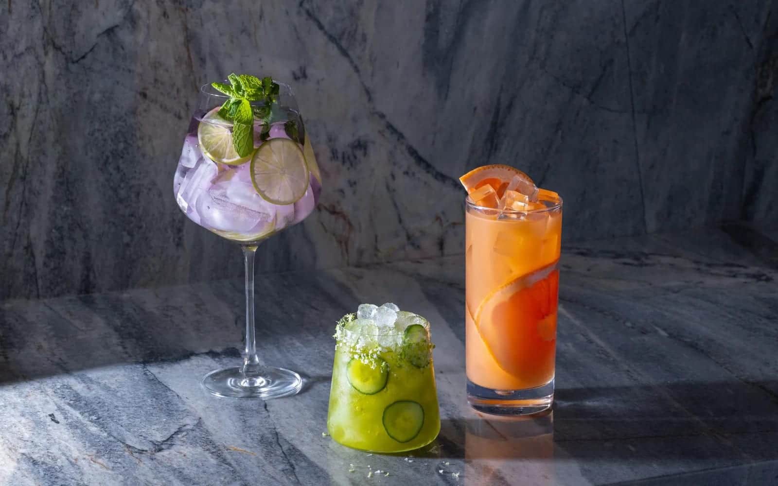 Cocktails over clear ice on a marble counter beside a Marvel undercounter unit
