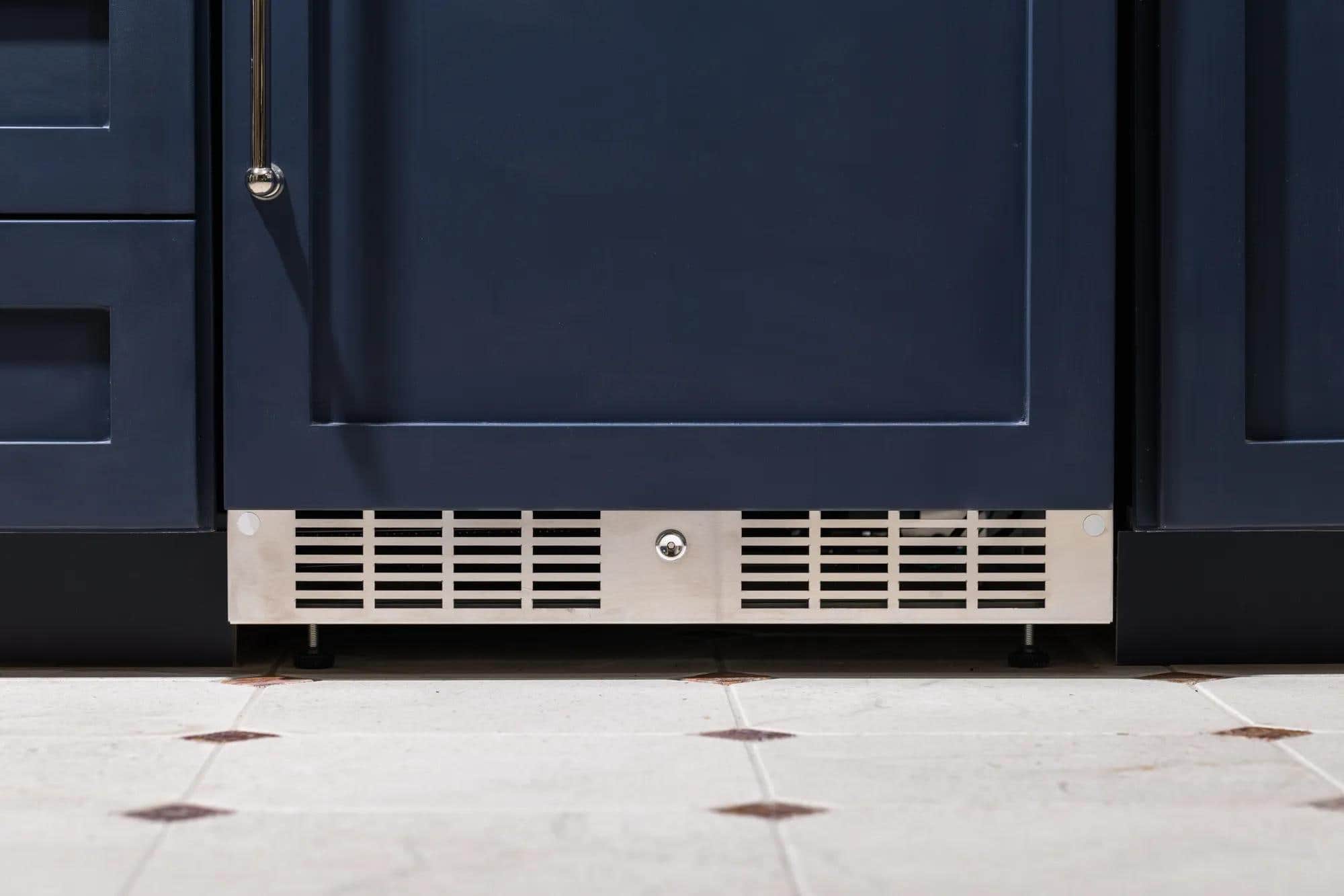 A panel-ready Marvel refrigerator behind a navy cabinet door, its toe-kick grille showing