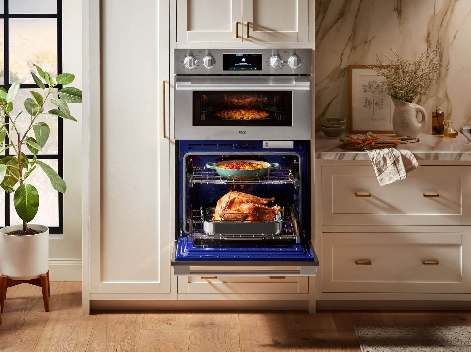 A stainless SKS double wall oven in cream cabinetry, potatoes roasting in the upper oven and the lower oven open on a roast turkey and a casserole