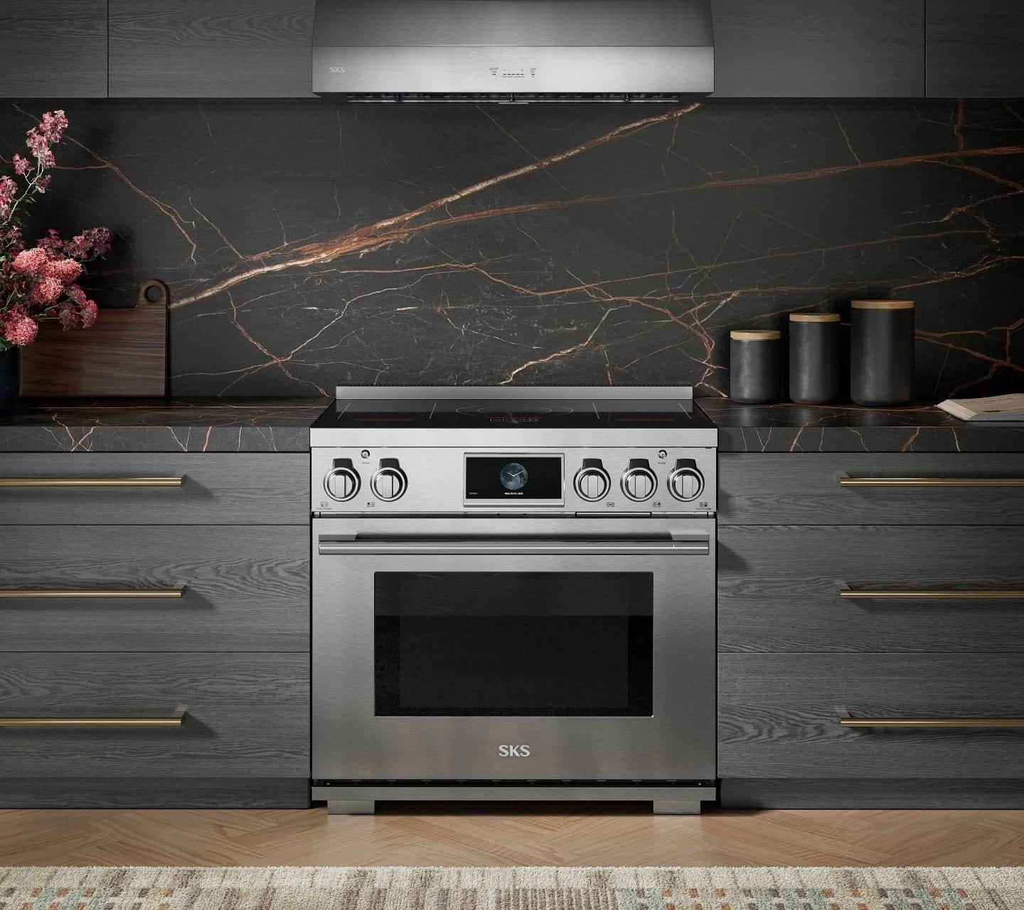 A stainless SKS induction range with a color touchscreen between charcoal oak drawers, against a black stone backsplash veined in copper