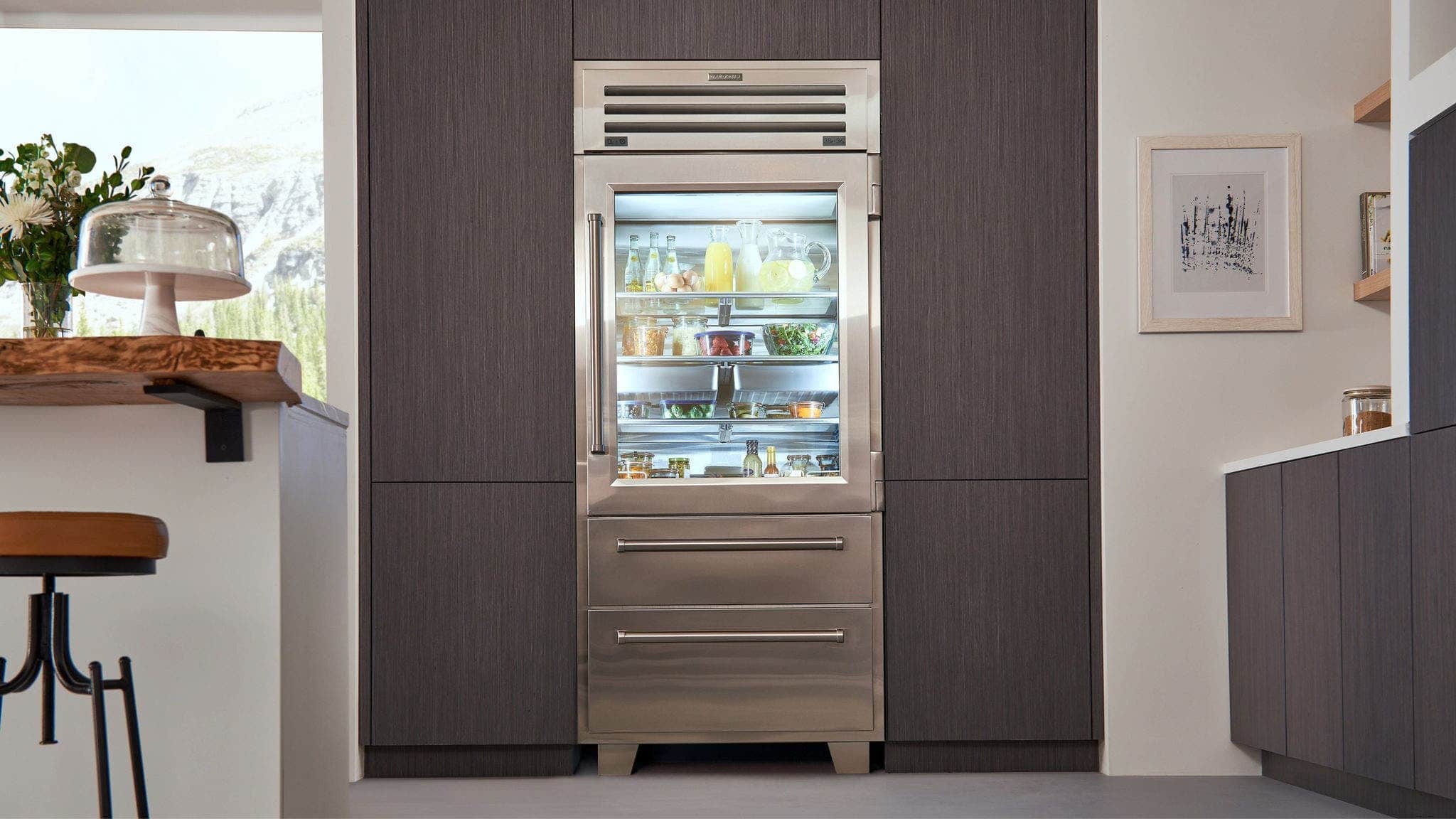 A stocked glass-door Sub-Zero refrigerator set into dark wood cabinetry
