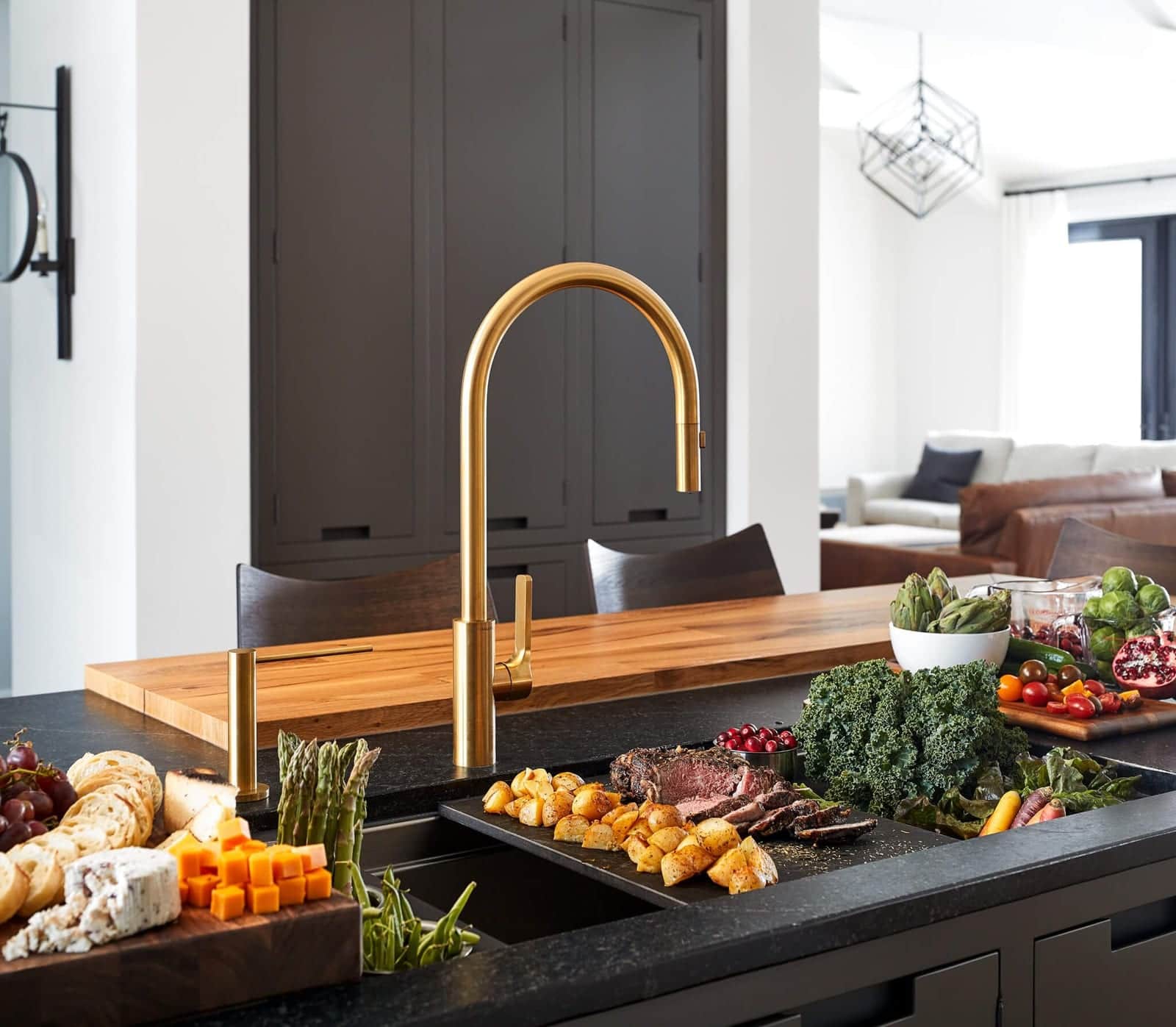 A charcuterie spread laid across a Galley workstation with a brass tap