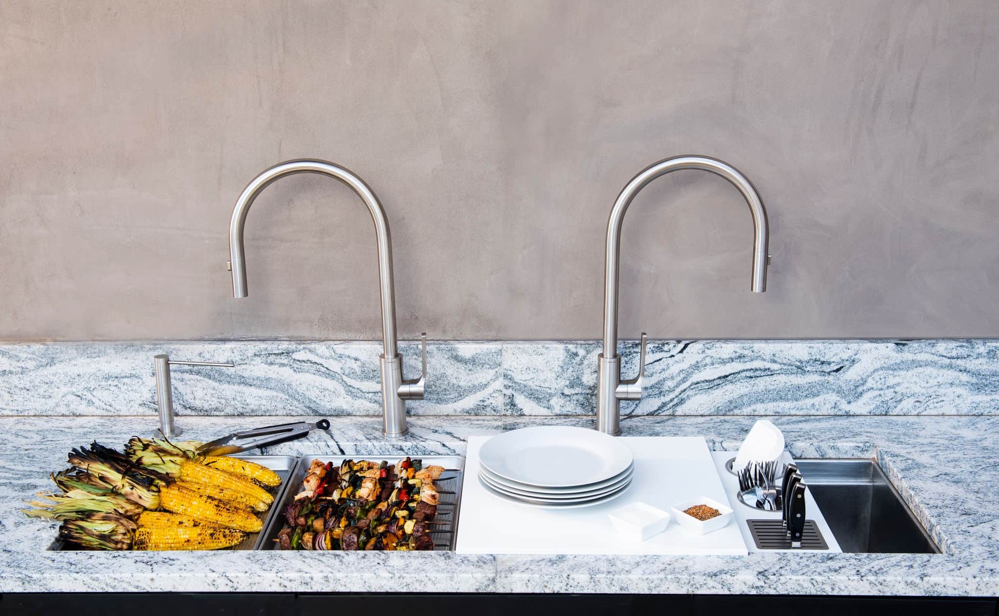 Grilled corn and skewers on the rail of an outdoor Galley workstation with two taps