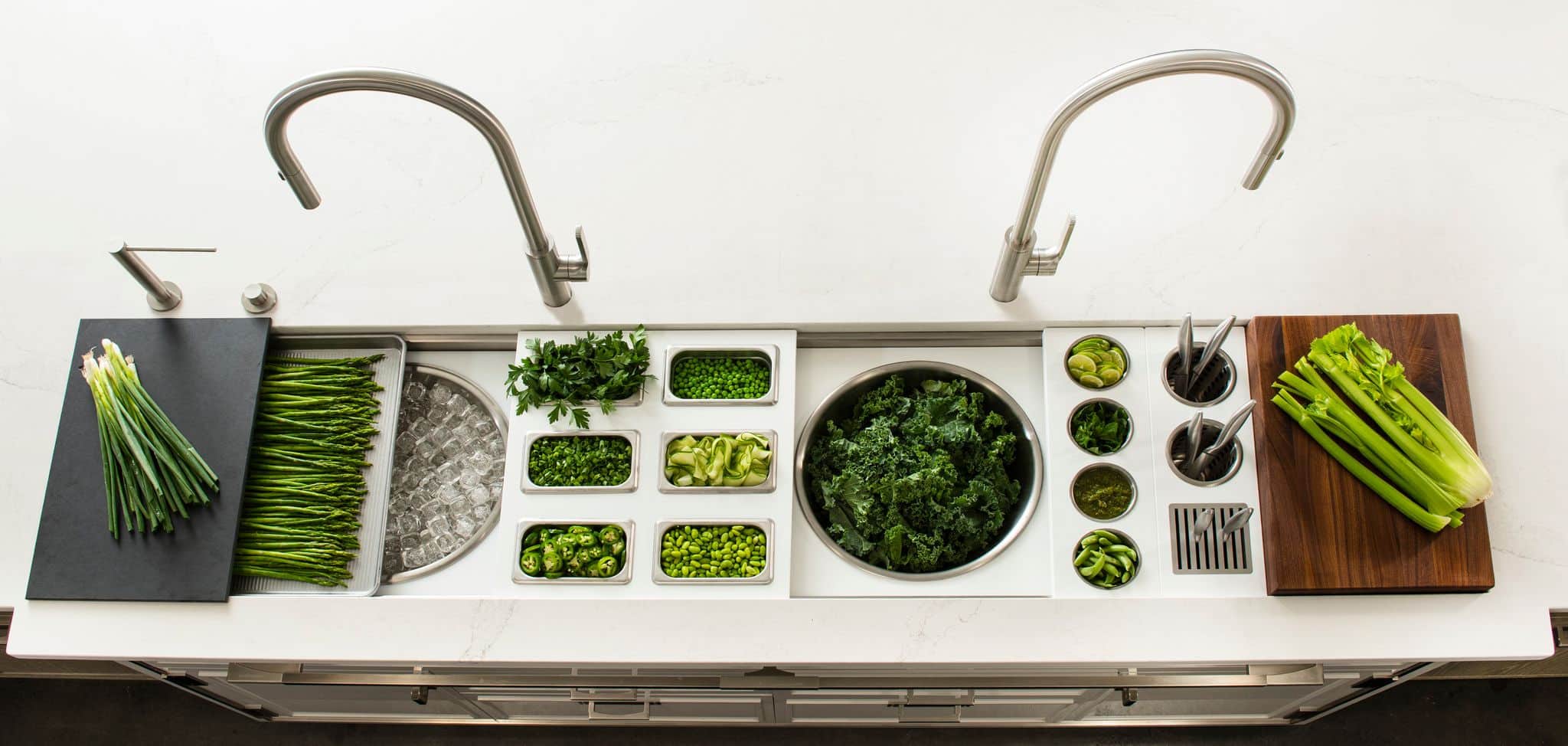 A Galley workstation laid out with green vegetables in its prep bowls and boards