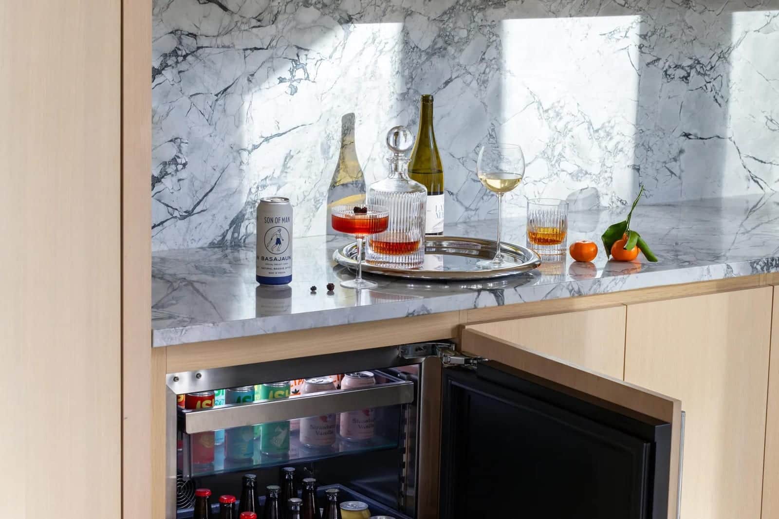 An open U-Line bar refrigerator set into a marble alcove