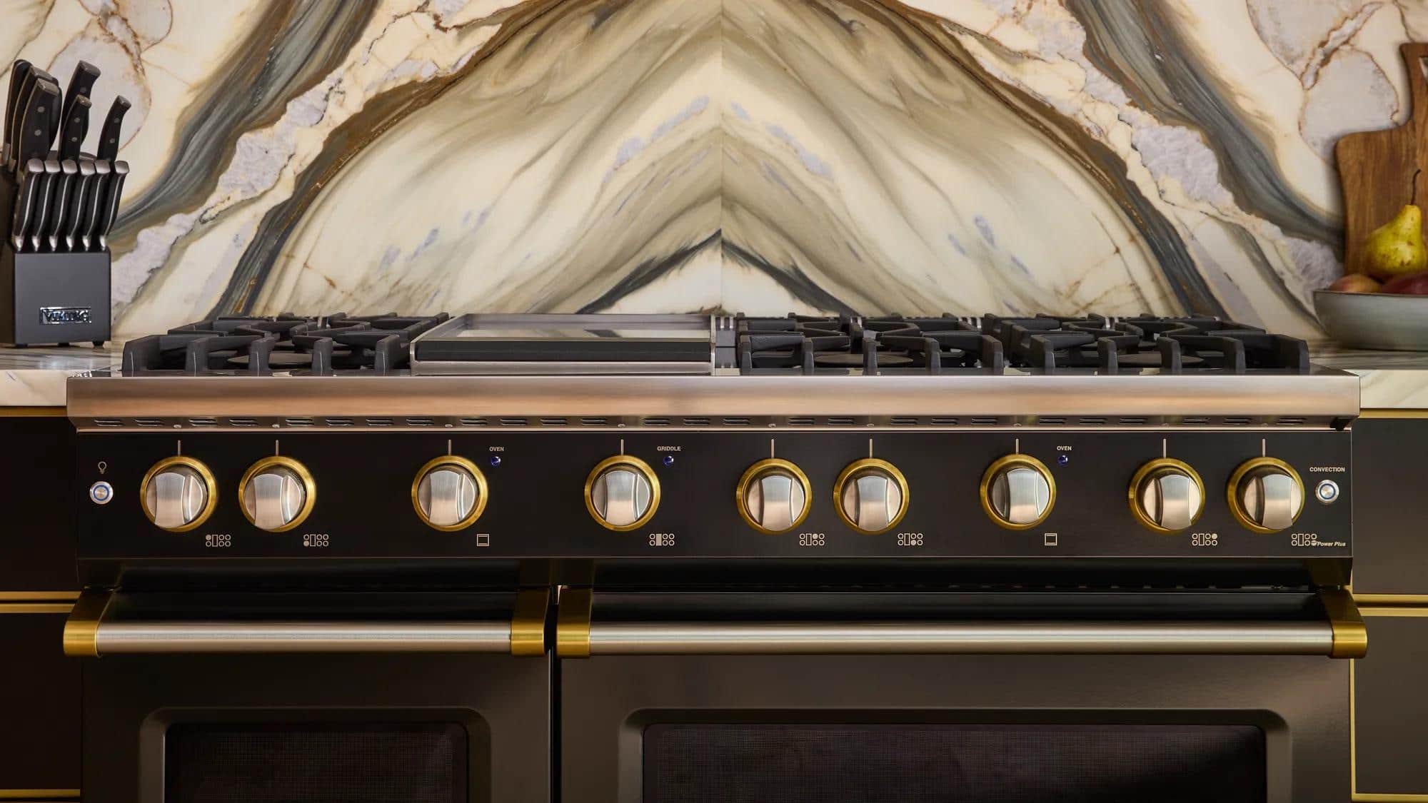 Close view of the brass control knobs on a black Viking range