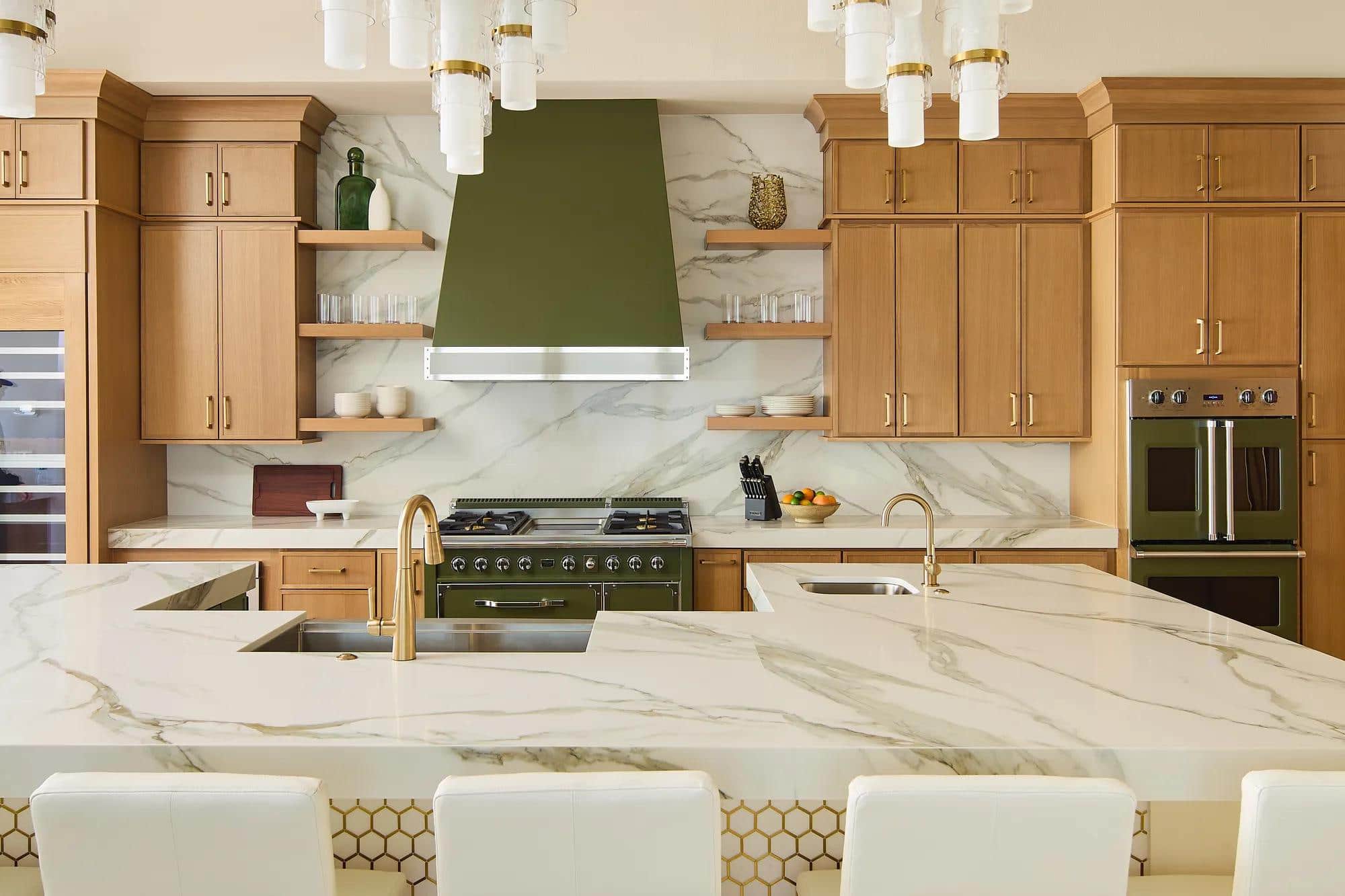 A Viking range under a green hood in an oak kitchen with a marble island