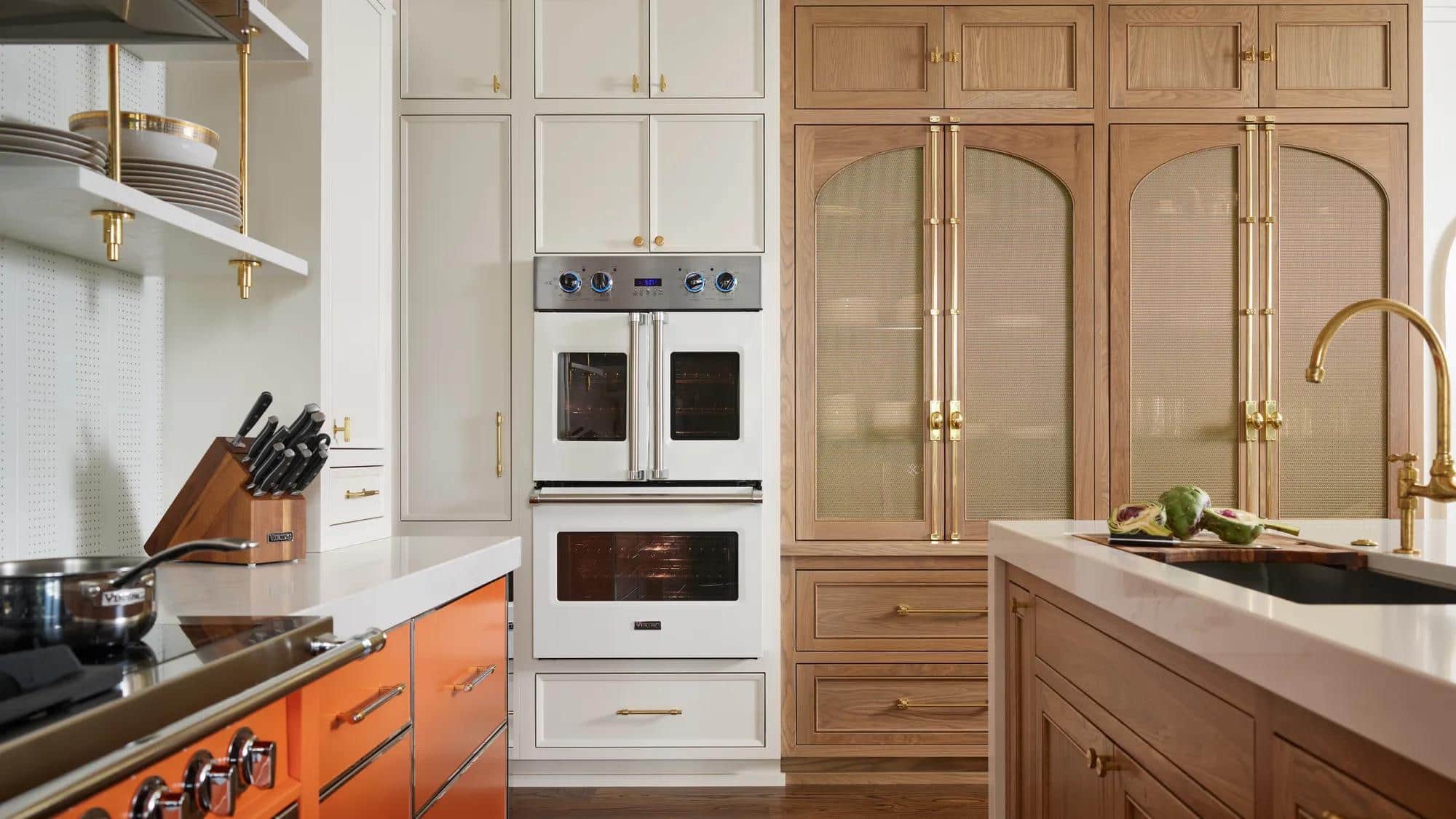 A white Viking double wall oven with French doors beside oak and fluted glass cabinetry