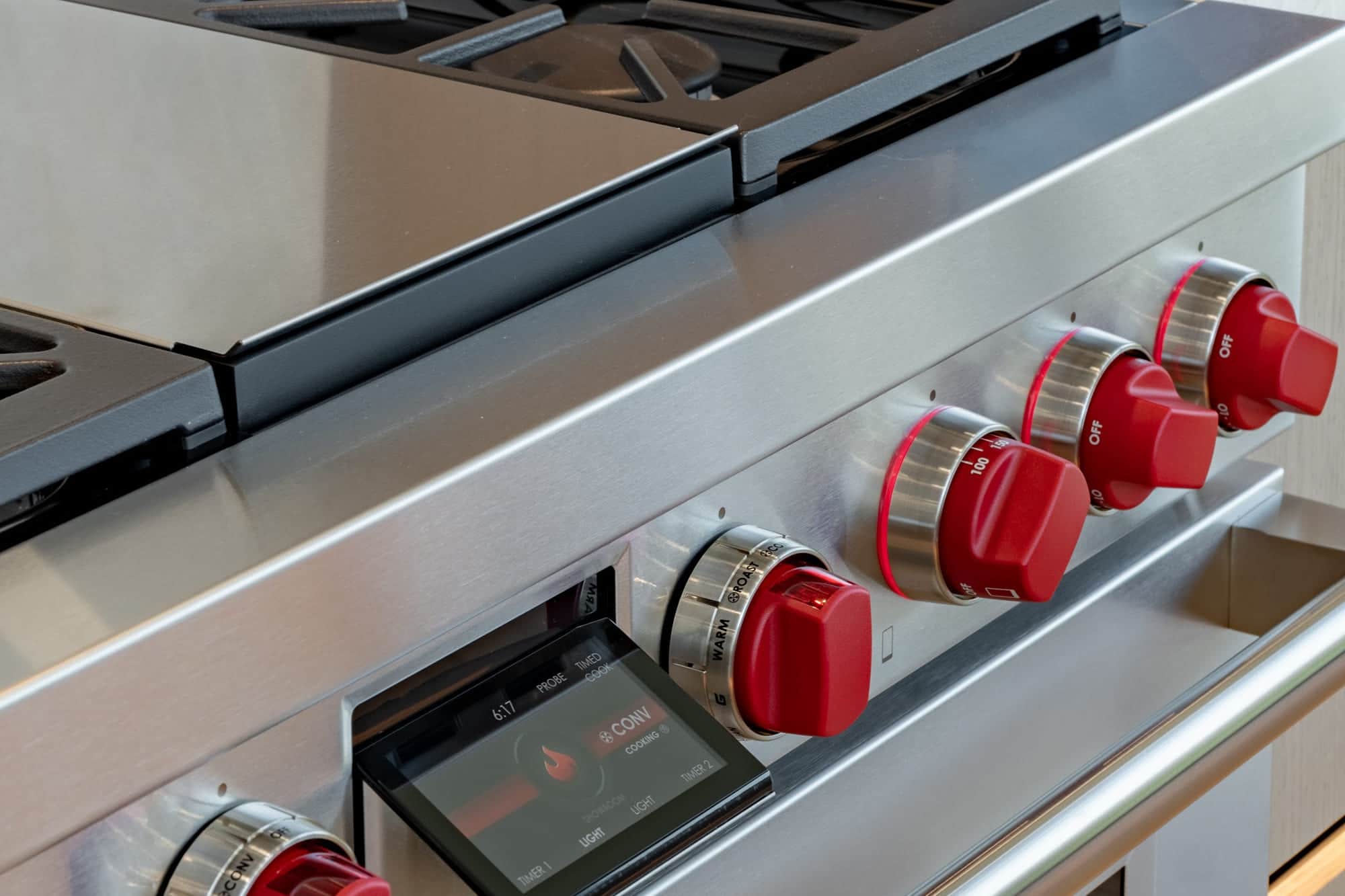 Wolf professional range on the Post Falls showroom floor, red control knobs and a lit cooking display set along the stainless fascia